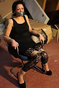 The abduction went well: captive girl is at the warehouse tape-gagged and chair-tied  Submissed